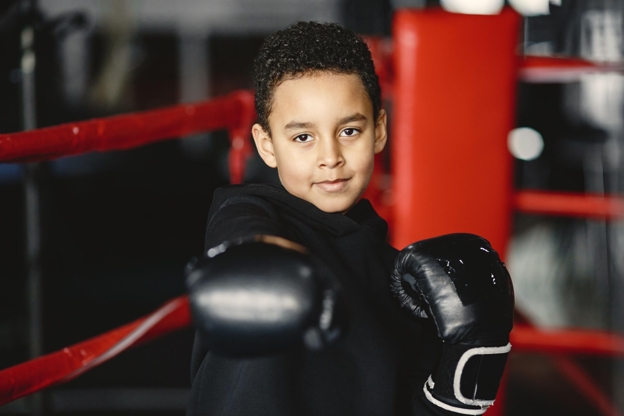 niño con guantes de box mostrando un puño a la cámara