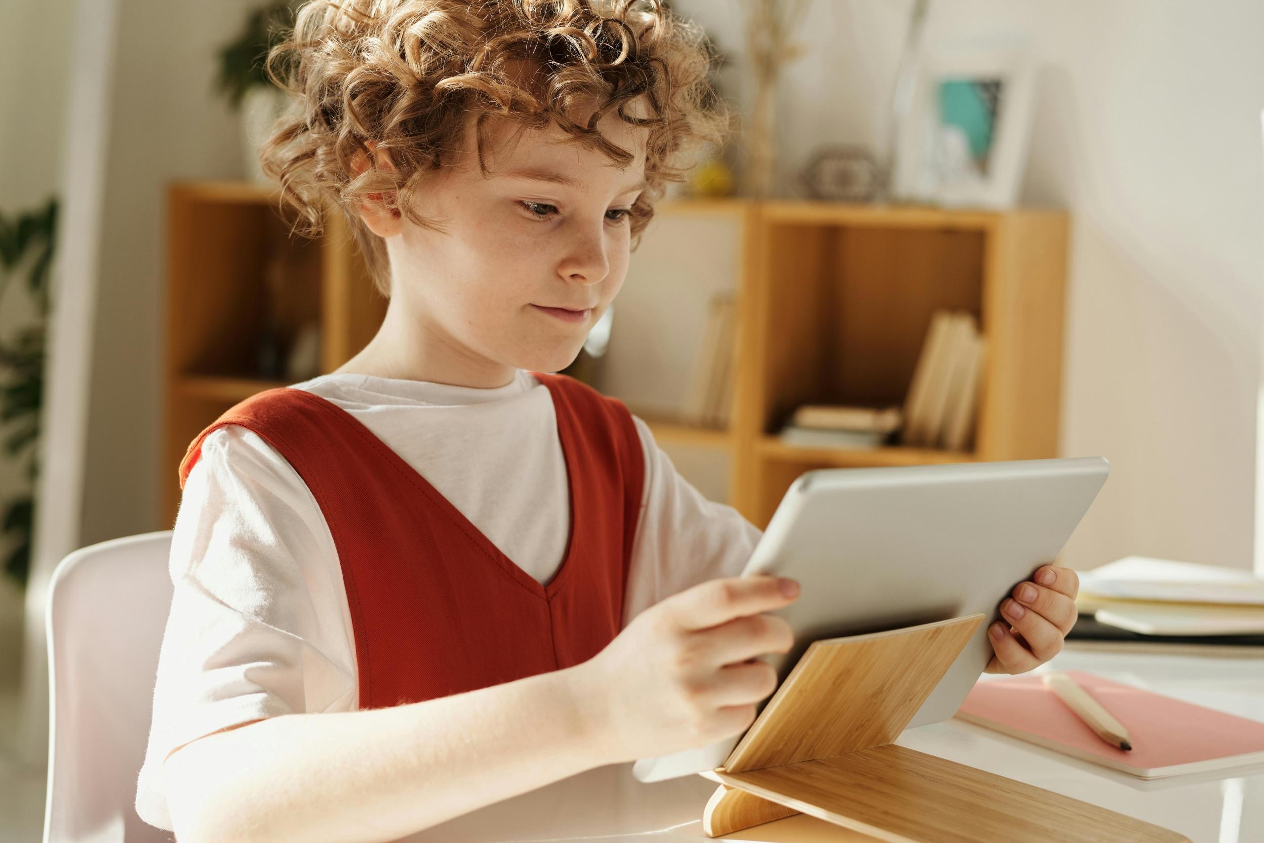 niño sosteniendo una tablet sobre un escritorio