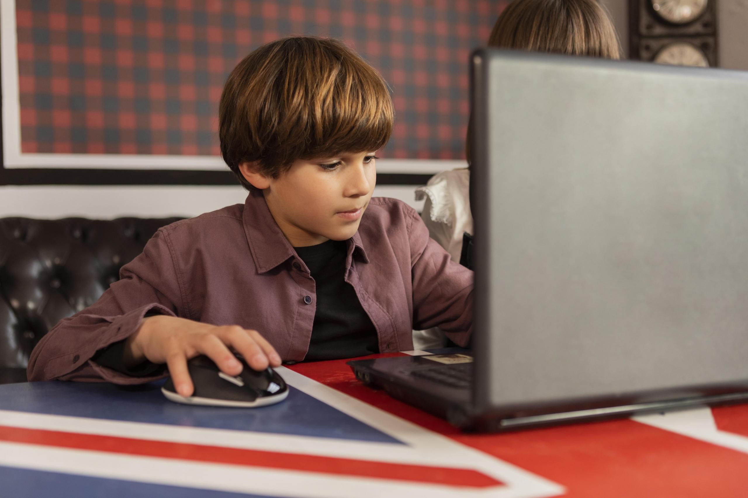 niño estudiando con una laptop sobre mesa de bandera inglesa