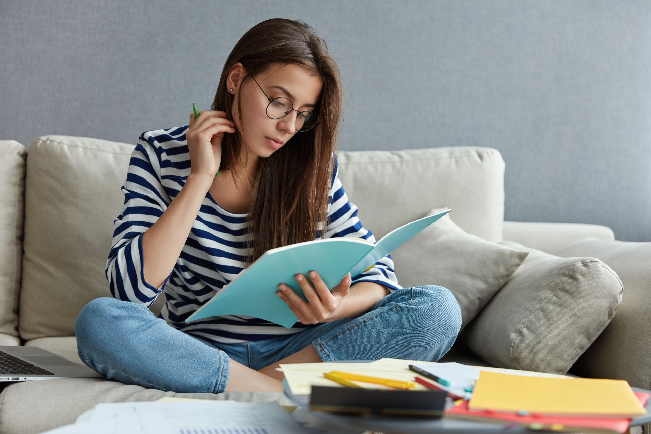 chica leyendo libros sentada en un sofa