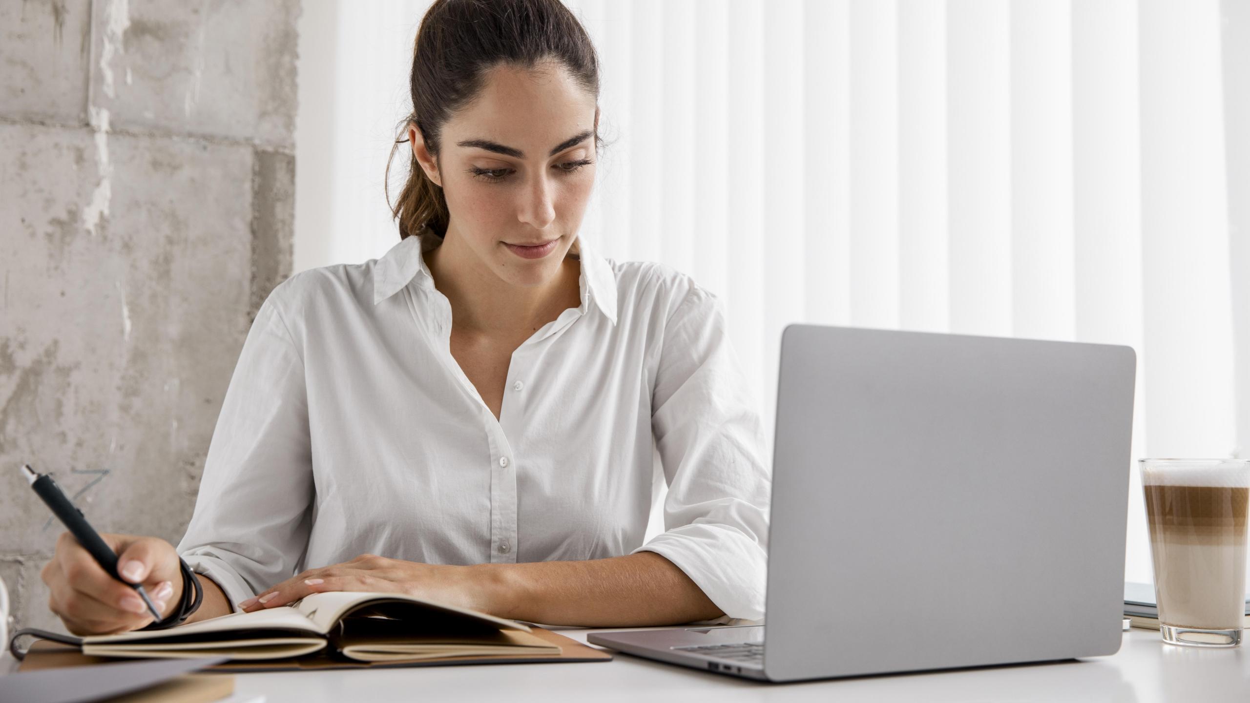 chica estudiando con su laptop y realizando anotaciones en su cuaderno