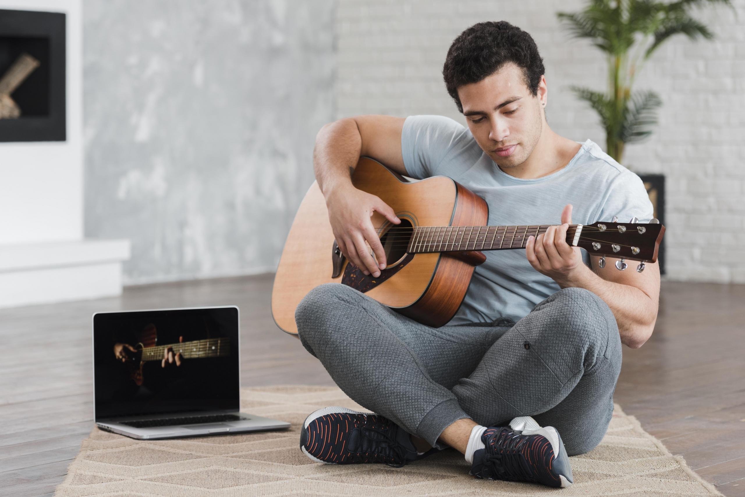 chico tocando guitarra sentado en el suelo