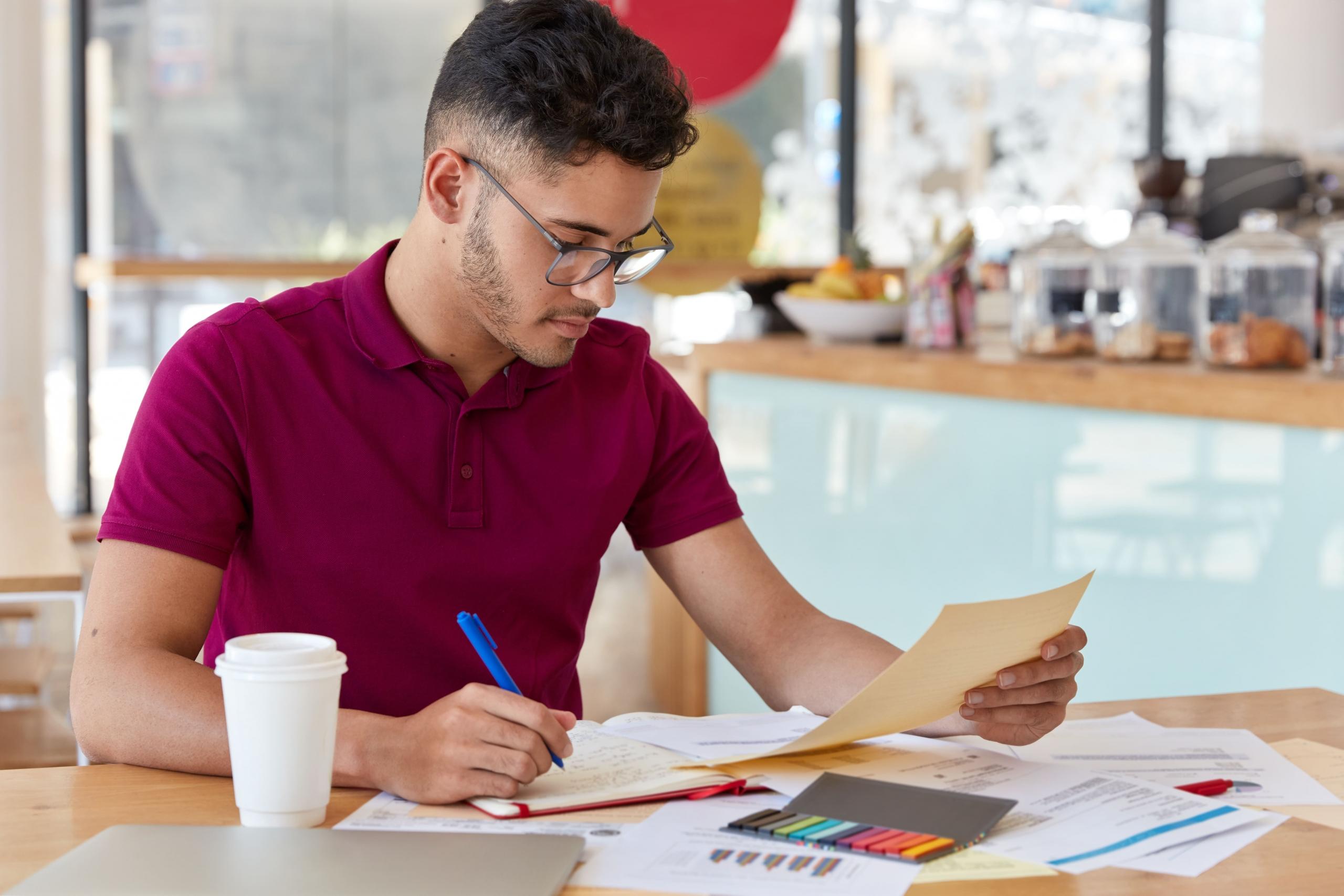 joven estudiando con sus apuntes y notas sobre una mesa