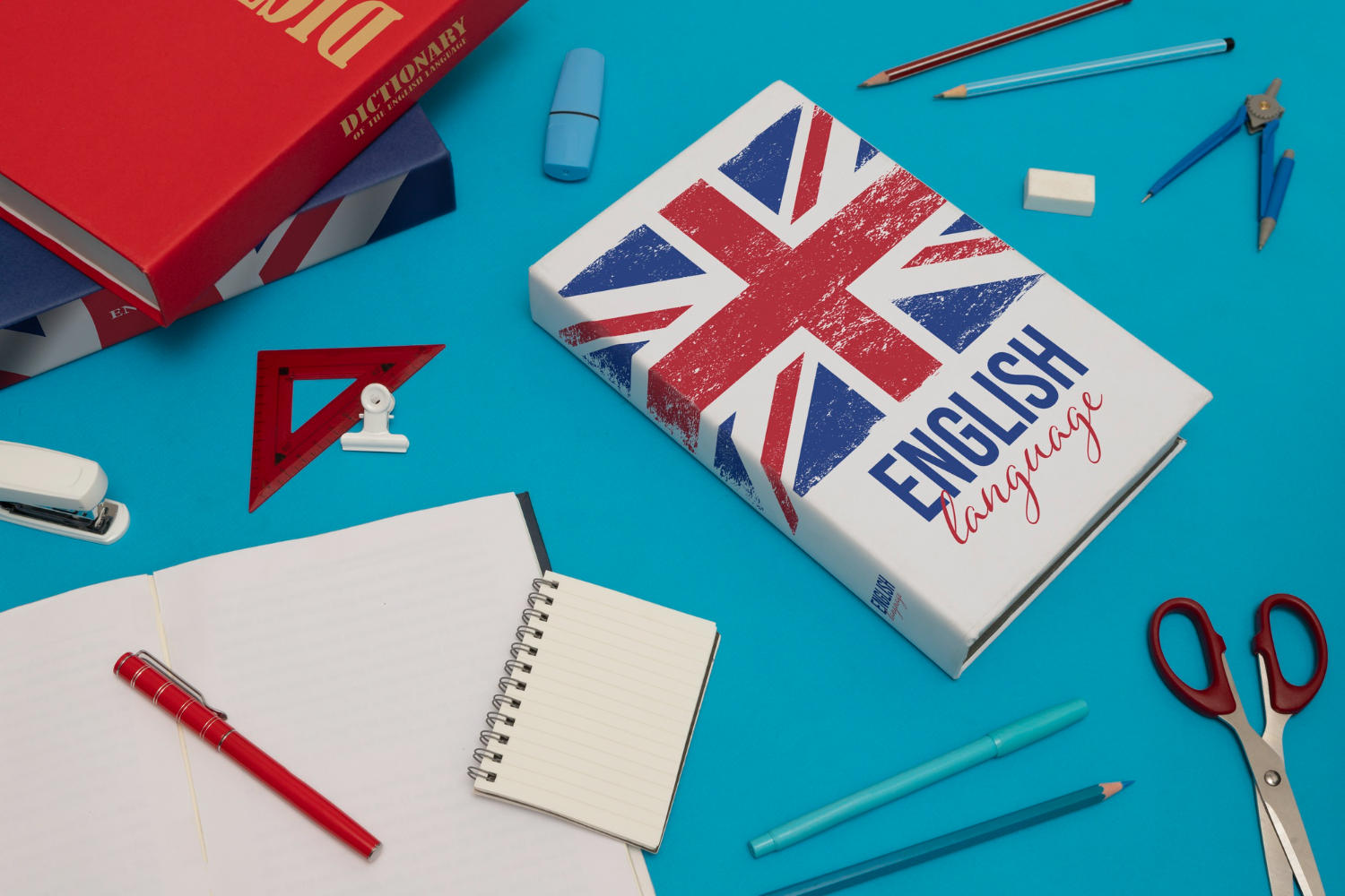 Libro de English Language sobre una mesa con varios útiles; hojas, tijeras, escuadra papeles etc.
