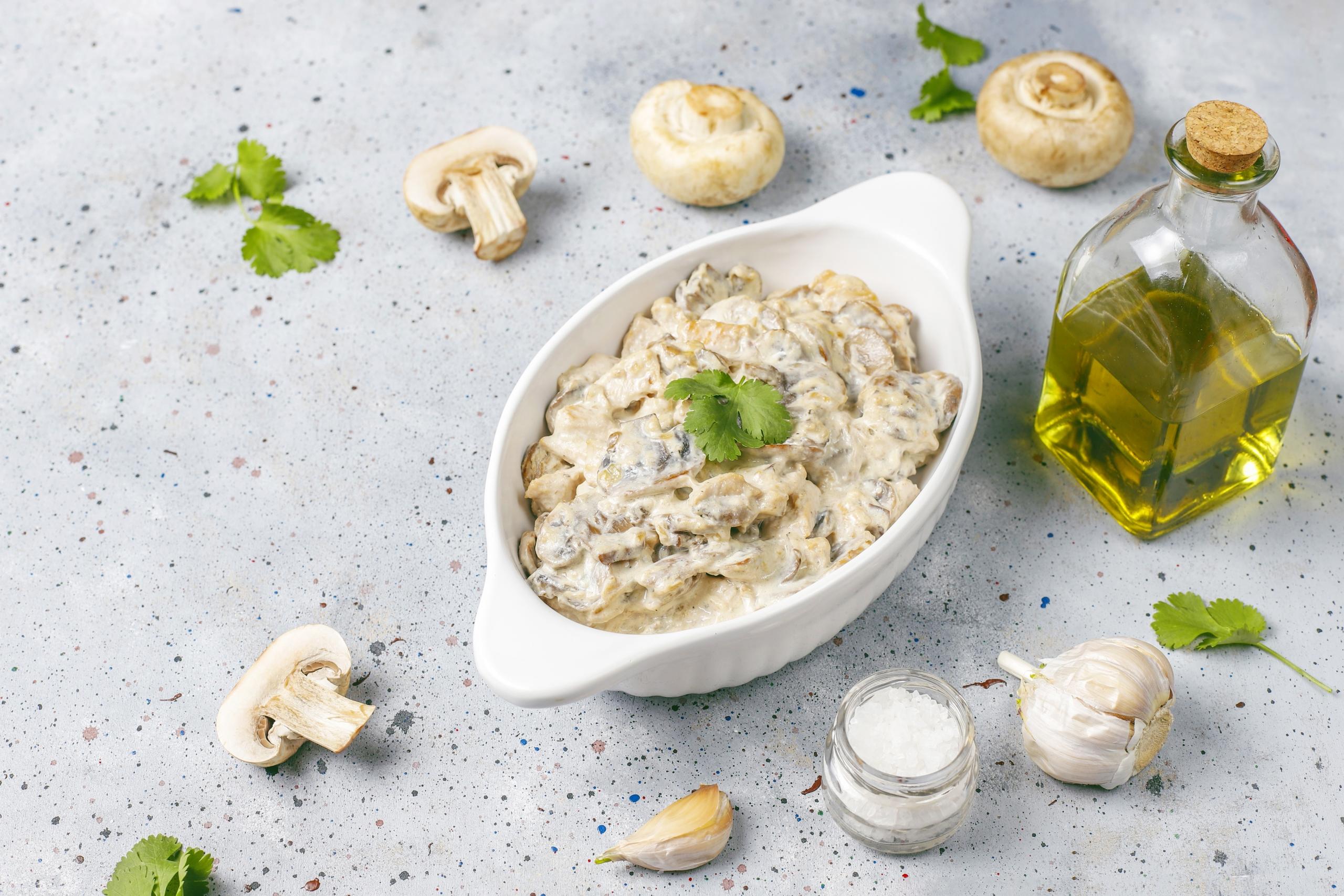 plato con crema de champiñones junto a una botella de aceite de oliva y champiñones cortados alrededor