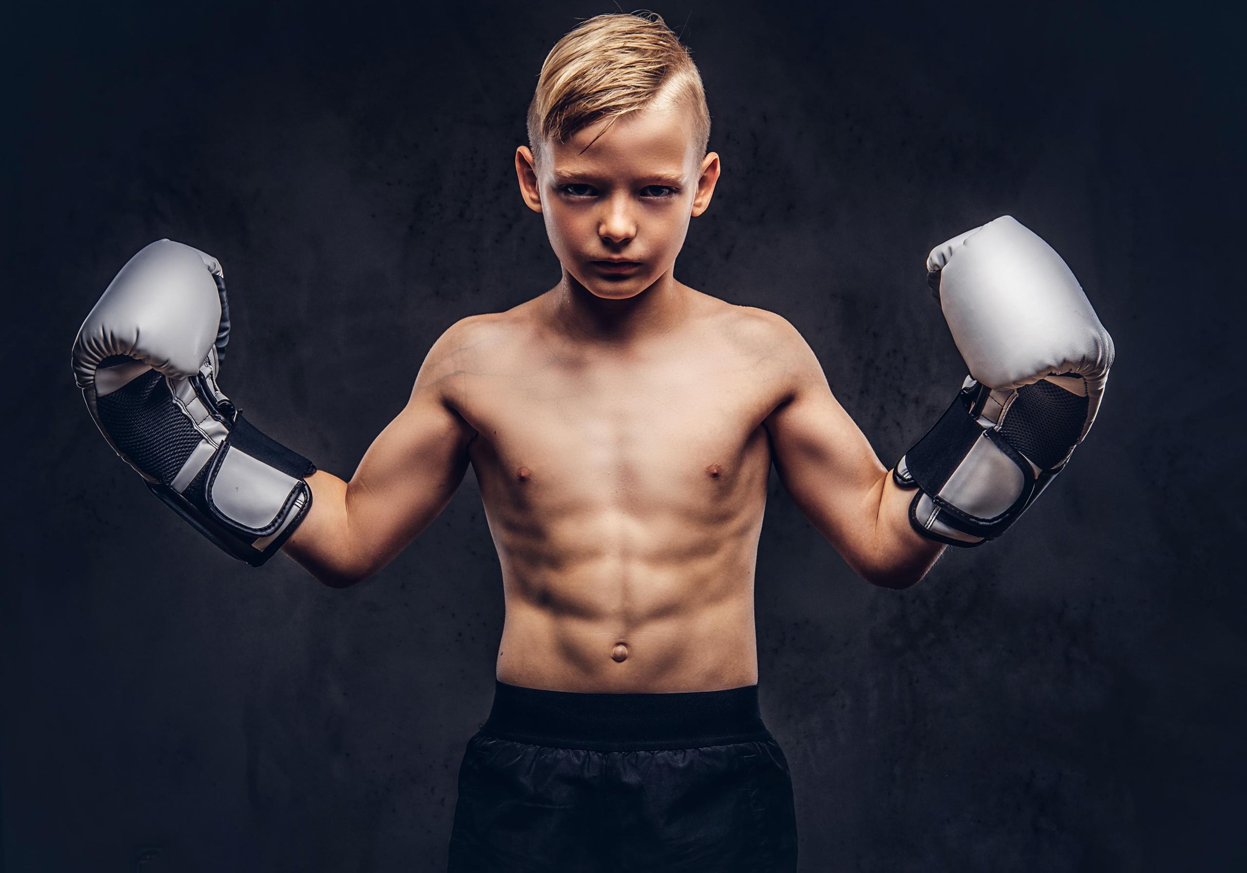 niño serio mirando a la cámara con guantes de box en ambas manos