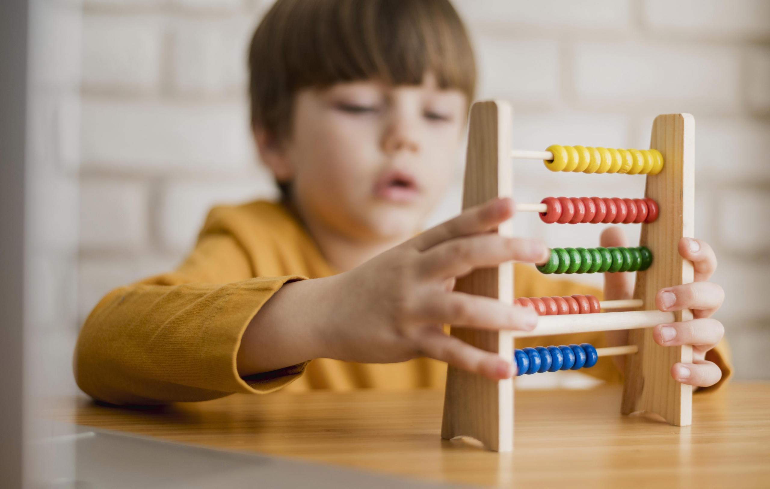 niño jugando con un ábaco de colores