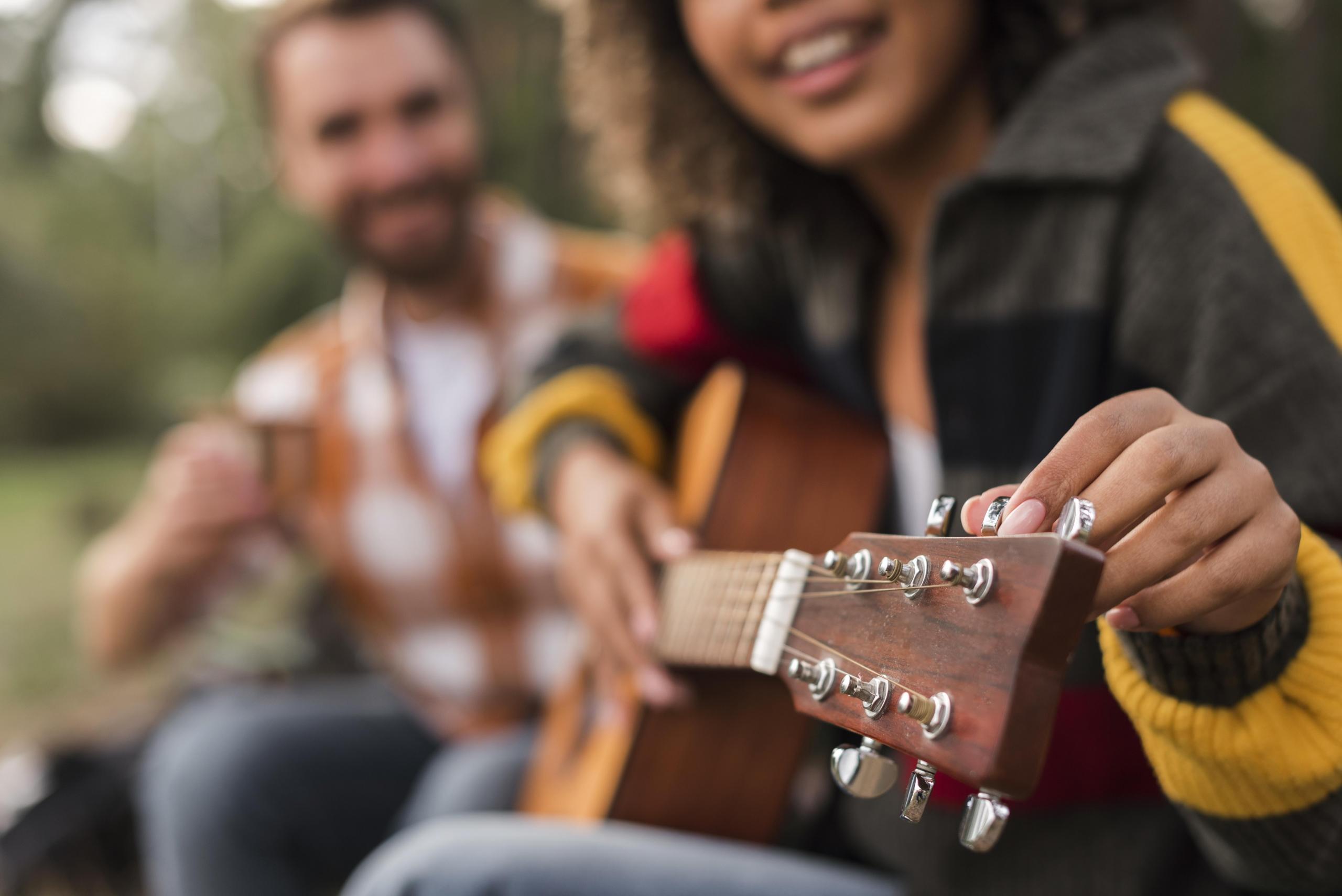 chica sonriente ajustando las cuerdas de su guitarra