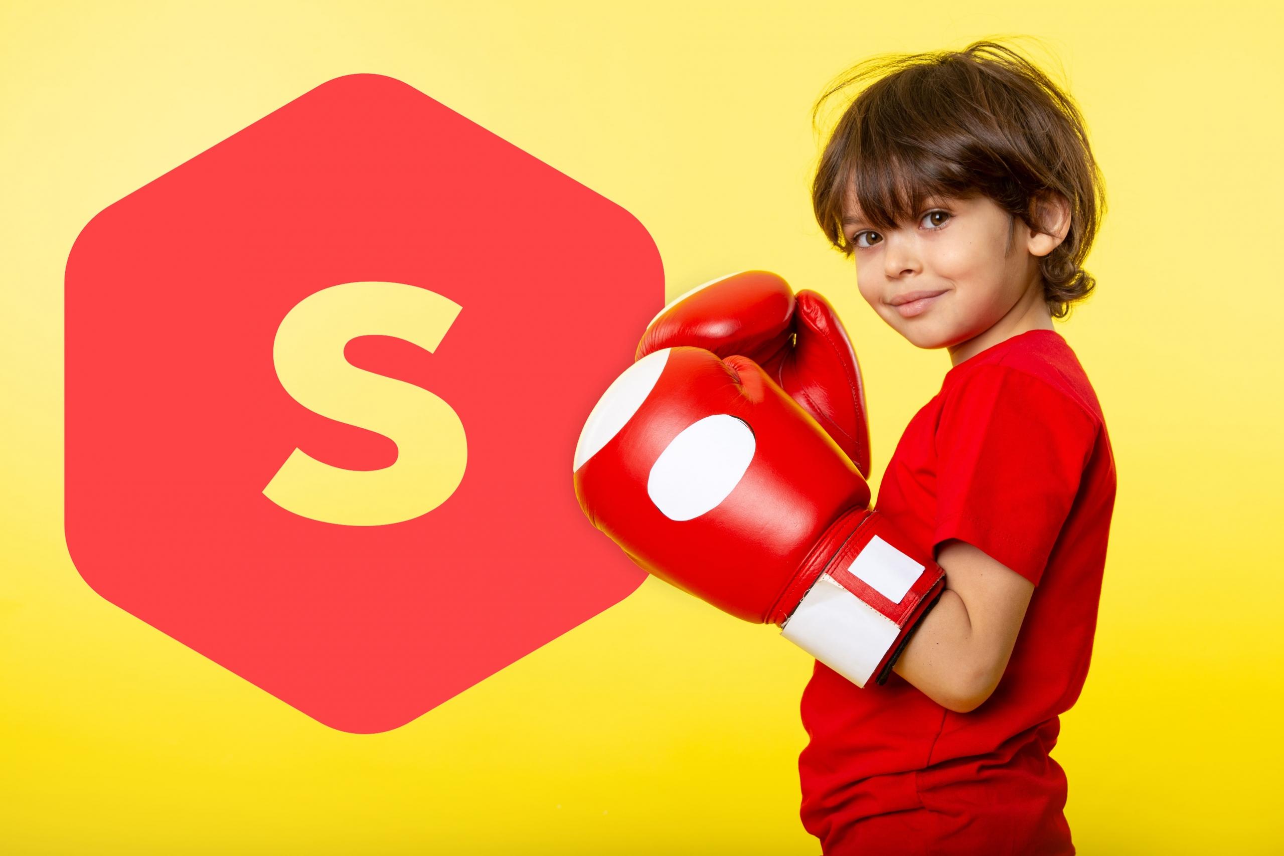 niño con guantes de boxeo y polo rojo rojo con guantes en posición de defensa con logo gigante de superprof perú a un lado