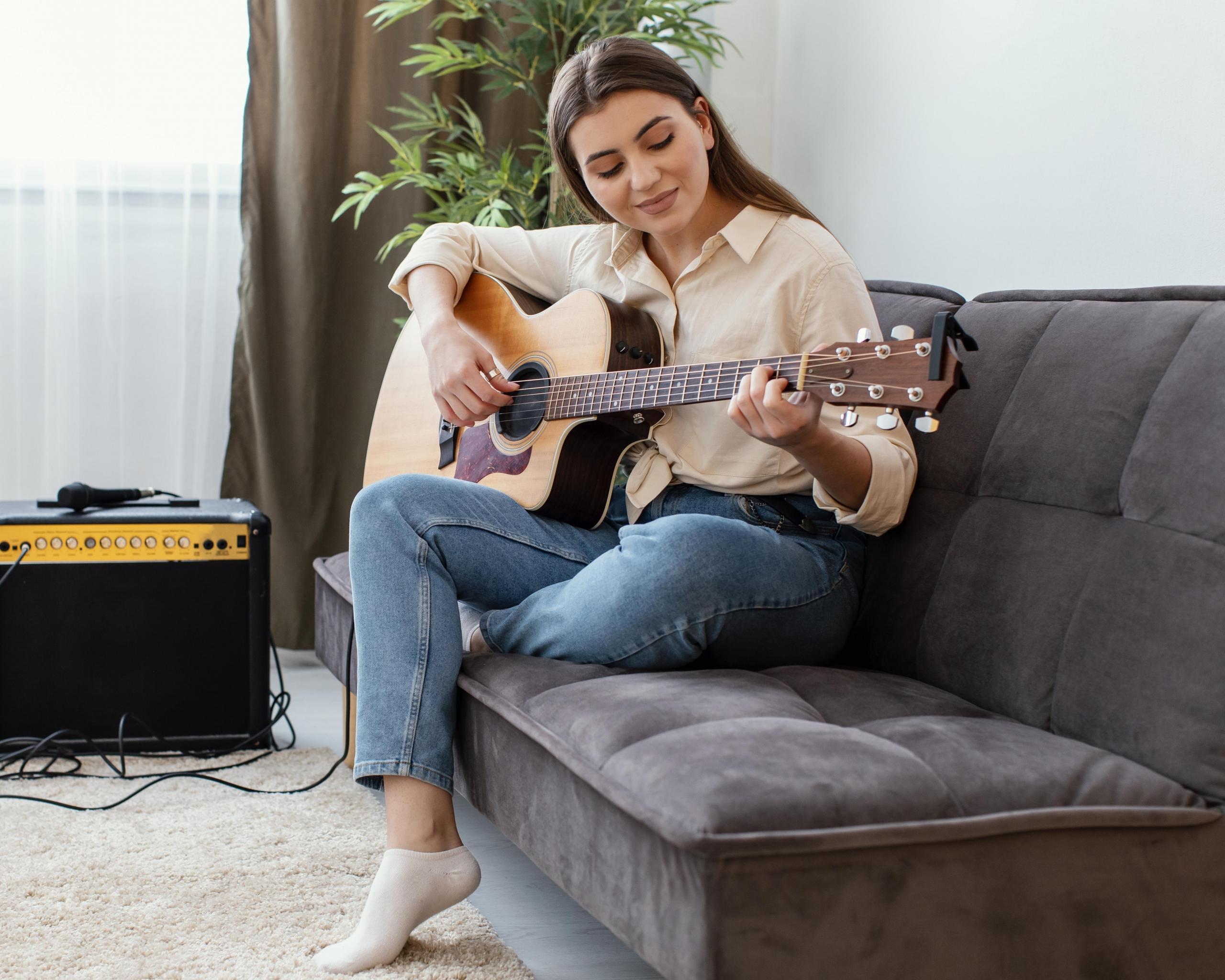 chica tocando guitarra en sofa