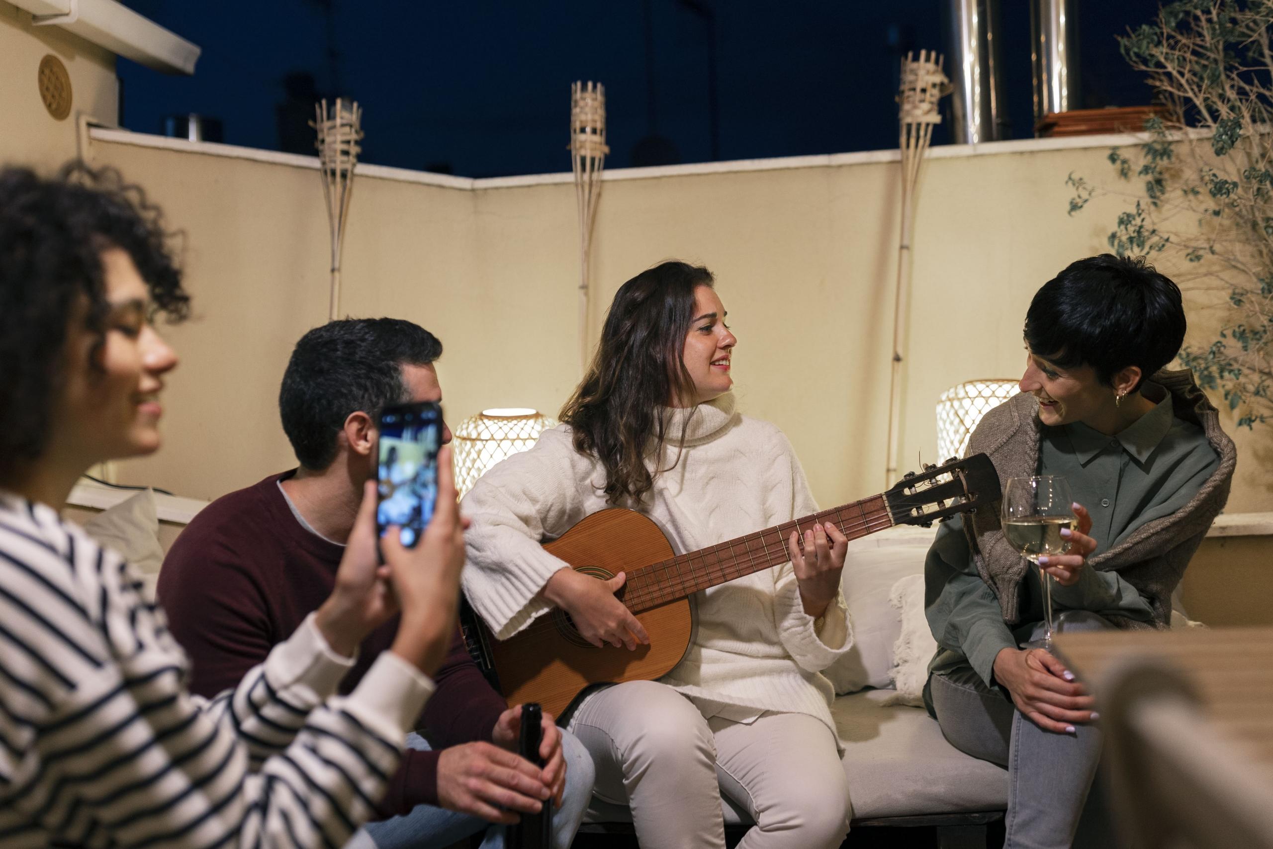 chica tocando una guitarra a su grupo de amigos reunidos