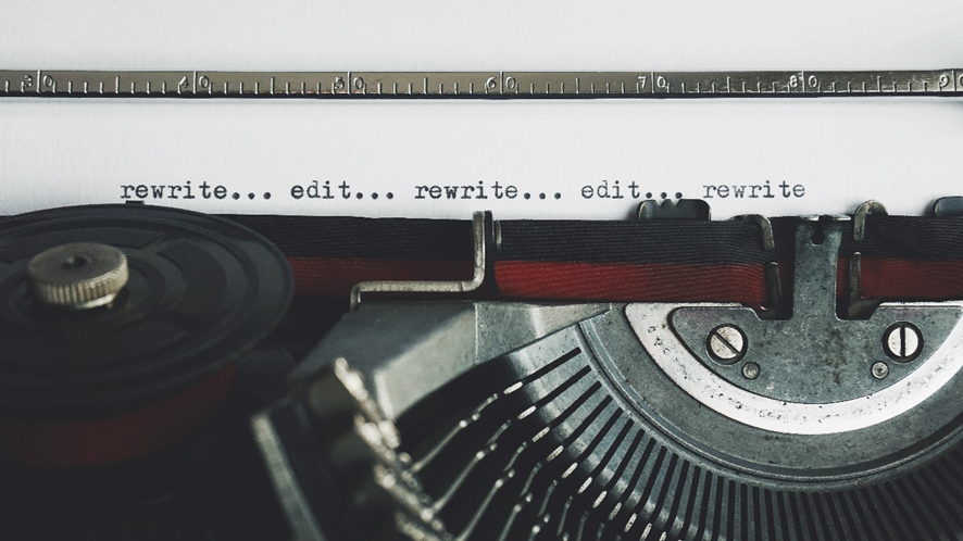 maquina de escribir con las palabras reescribe y edita, en inglés.