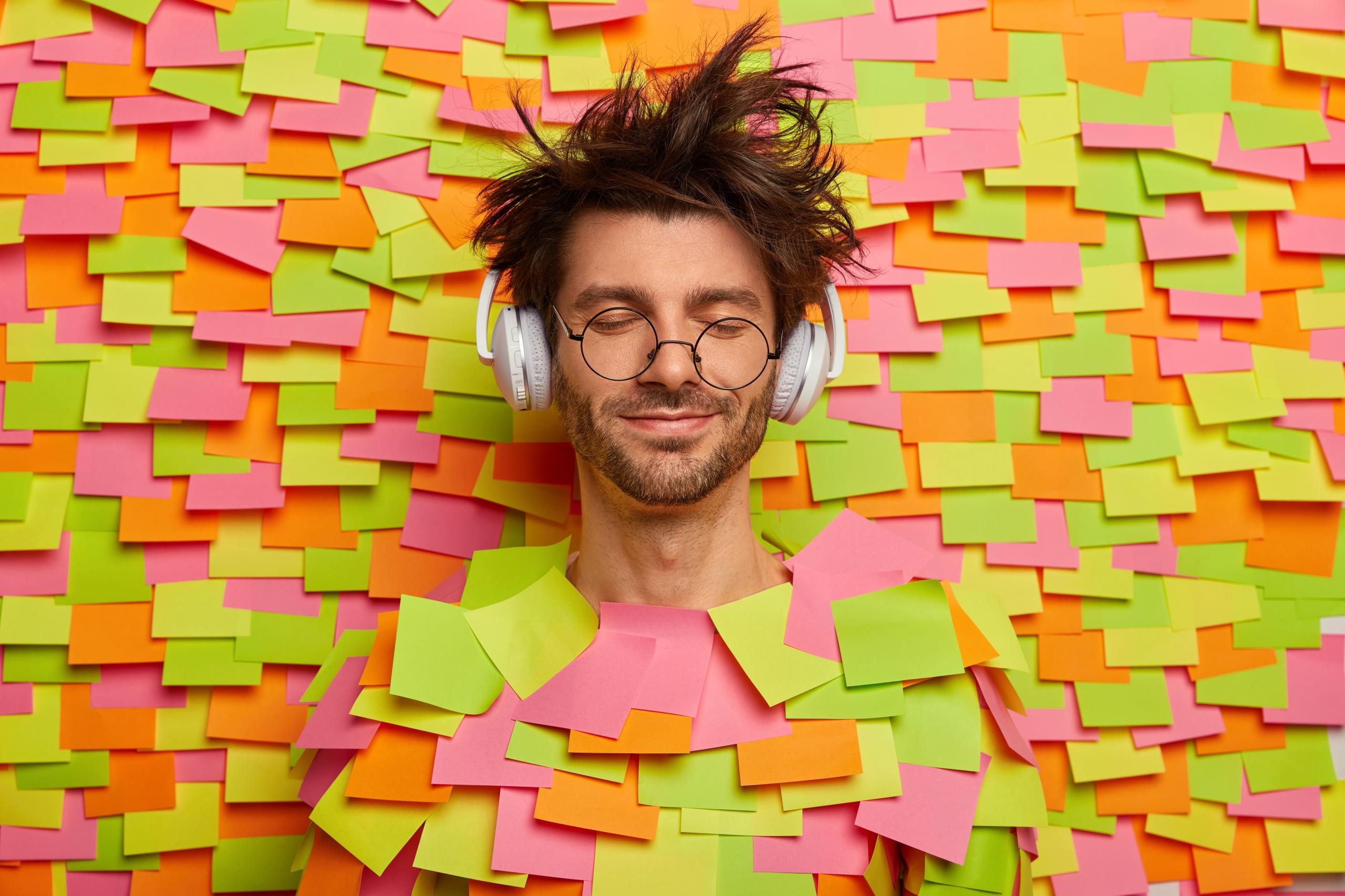 joven lleno de post its pegados encima suyo y en la pared