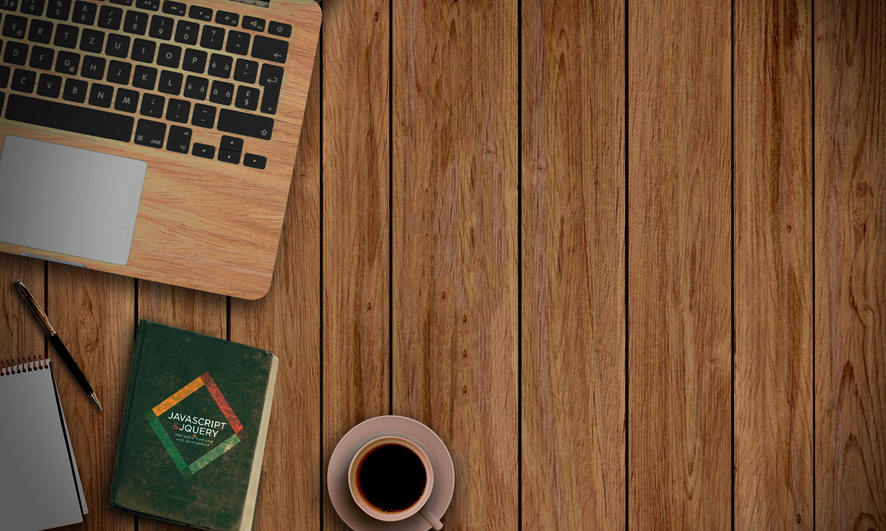 Una computadora, un café, un cuadernillo, y un lápiz sobre una mesa de madera