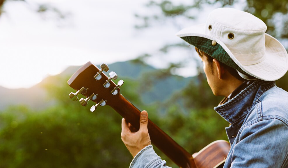 joven con sombrero de espaldas sosteniendo una guitarra