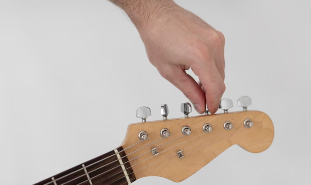 Una mano afinando las cuerdas de su guitarra
