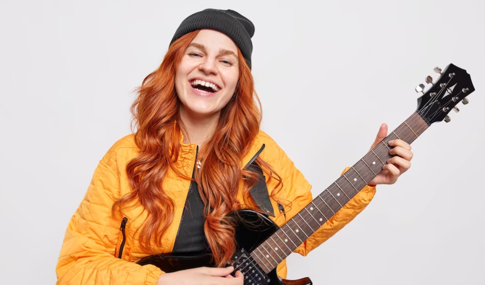 Chica pelirroja sonriendo con guitarra en manos