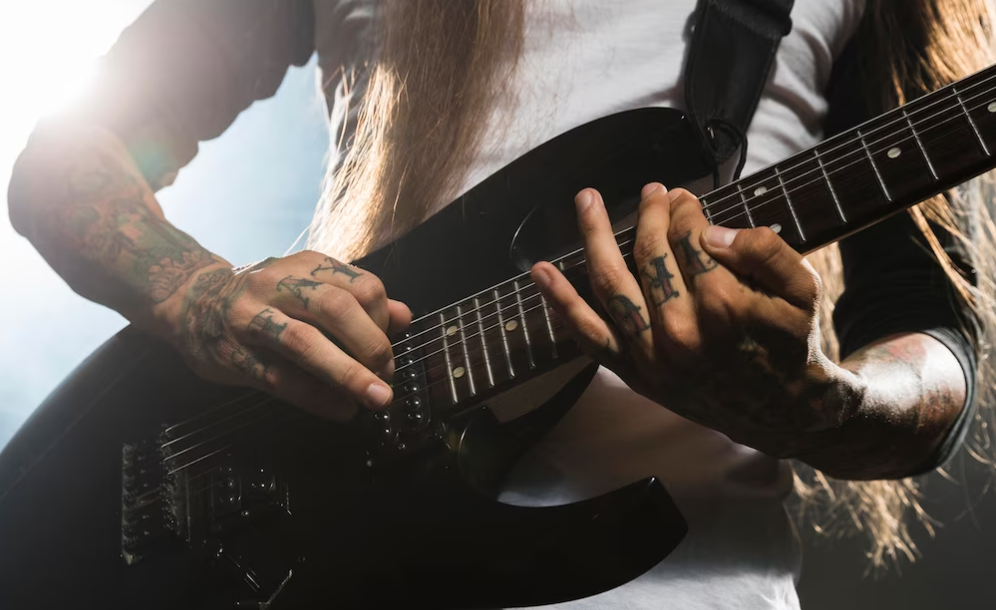 brazos de un hombre tatuado tocando la guitarra electrica