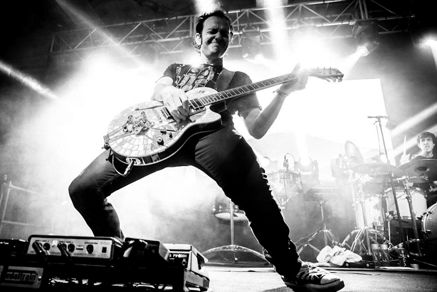 foto en blanco y negro de un guitarrista tocando sobre un escenario