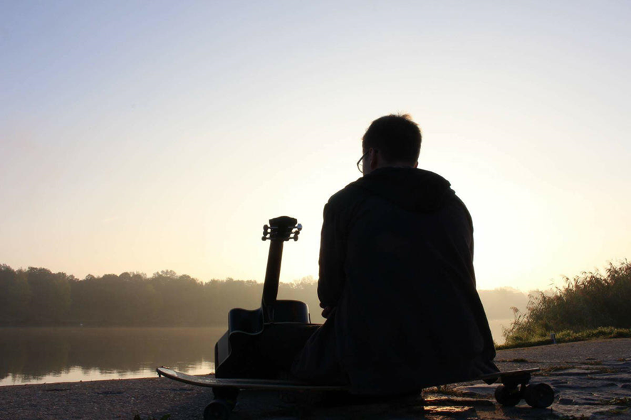Un hombre con su guitarra viendo el horizonte