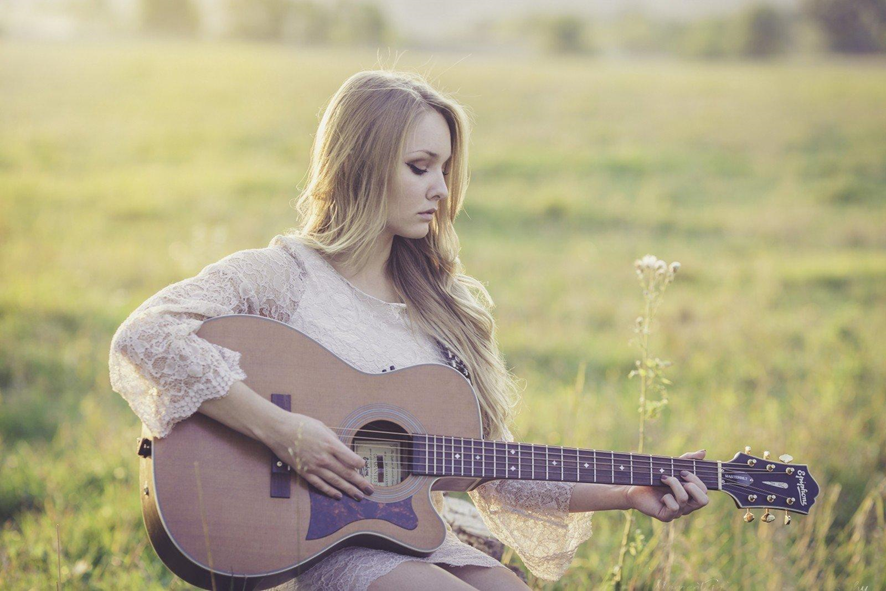 Chica tocando la guitarra en el campo