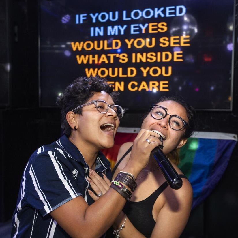 dos chicas con micrófonos cantando felices una canción en inglés