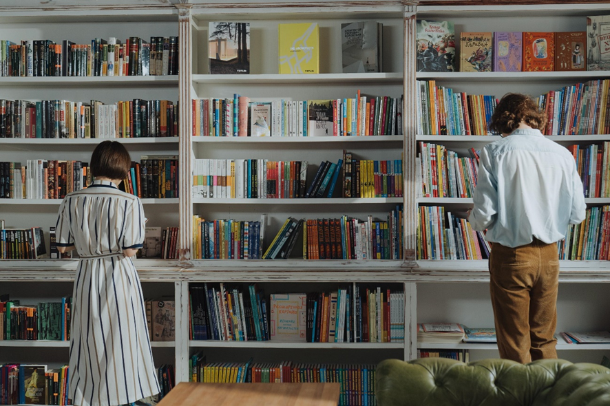 dos personas en la biblioteca leyendo libros