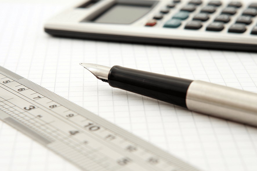 Una calculadora, una regla y un lapicero sobre una hoja