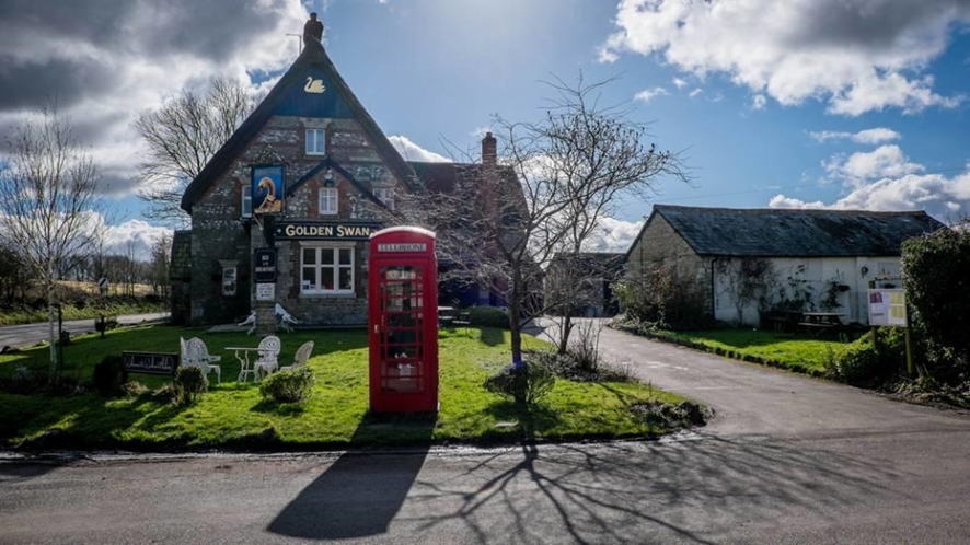 fachada de casa de campo y cabina roja de telefono