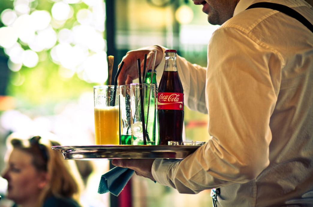 Mesero sirviendo una coca-cola.