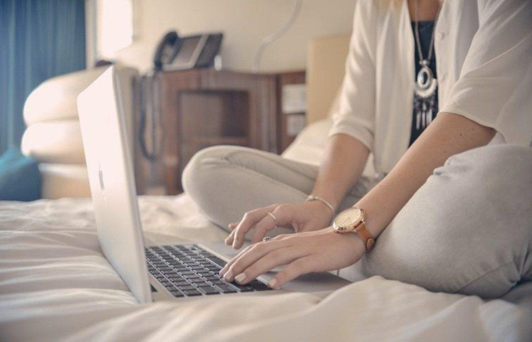 Chica usando su computadora en la cama