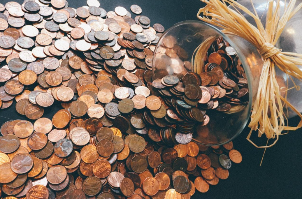Muchas monedas de centavos saliendo de un frasco