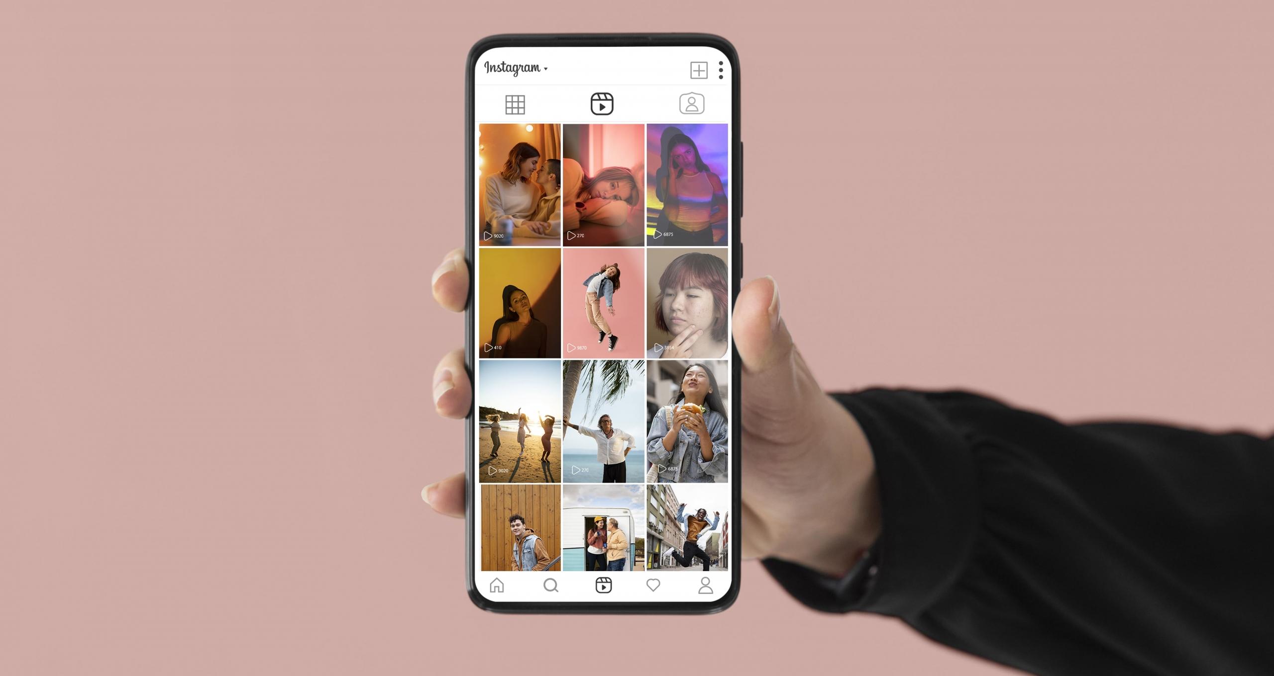 mano mostrando un celular con un feed de instagram lleno de fotos