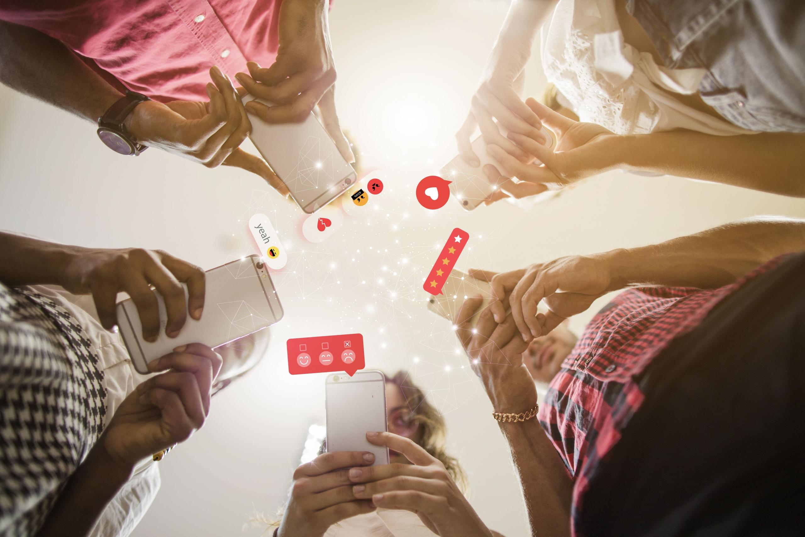 vista contrapicada de de 5 jovenes usando sus celulares y redes sociales