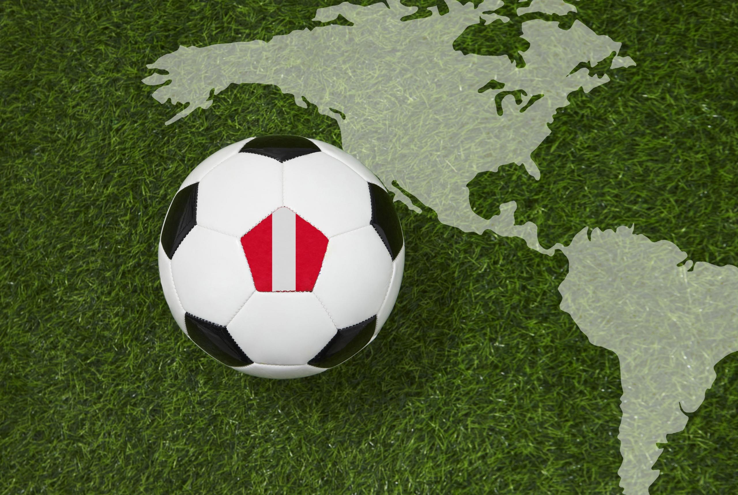 pelota de futbol con bandera de Perú sobre un grass con la silueta del mapa de América traslúcido