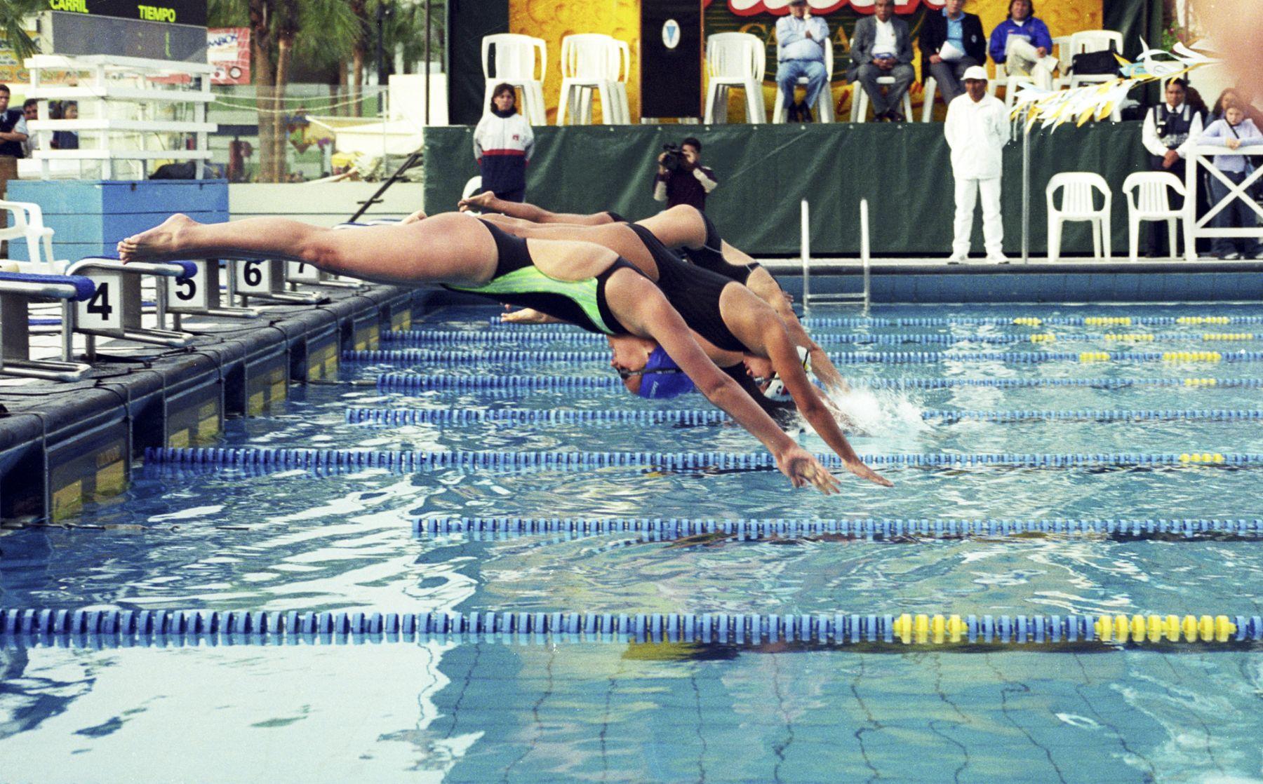 cuatro nadadores saltando a una piscina olimpica en una fila