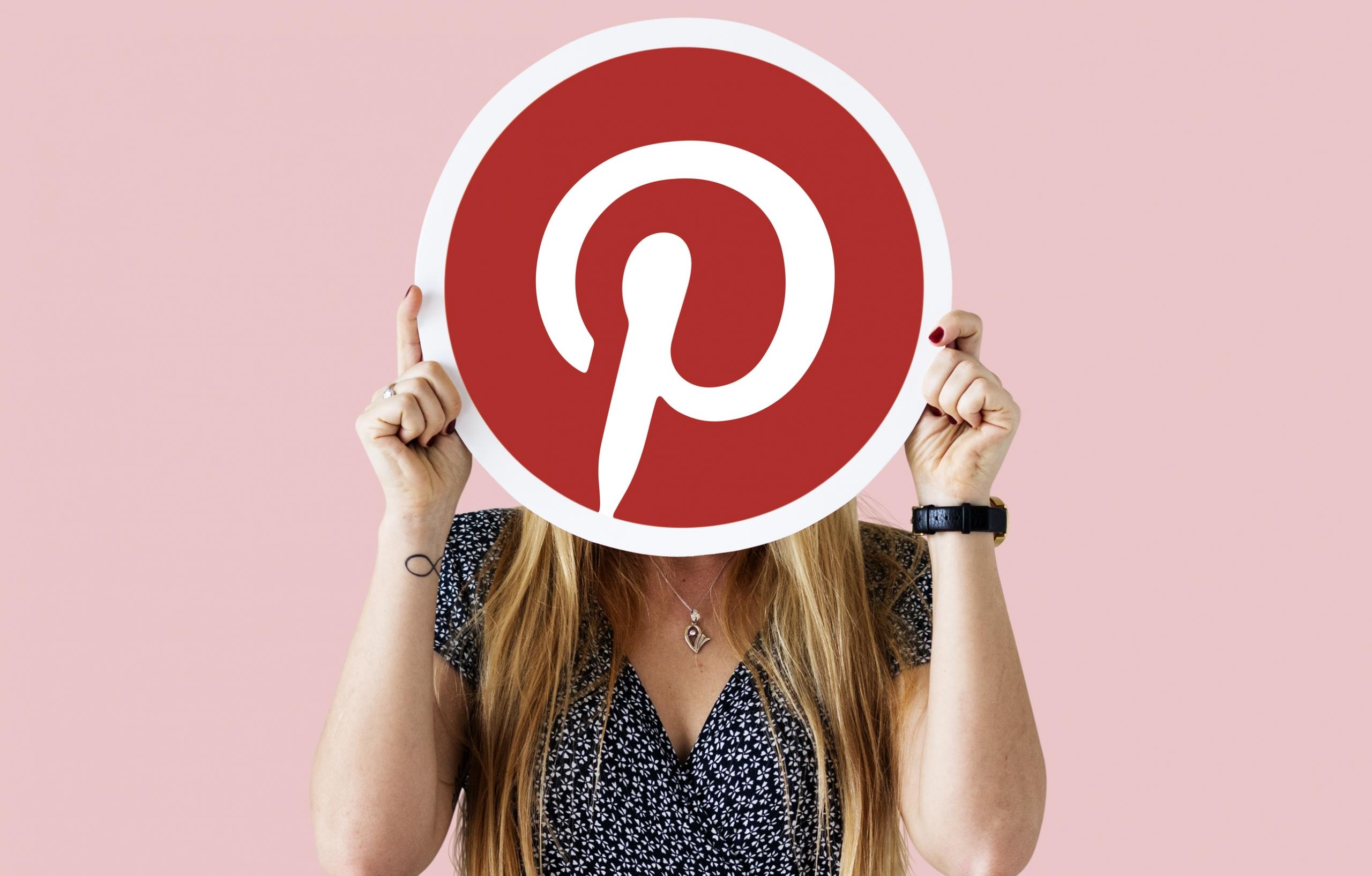 chica tapando su rostro con un cartel del logo de Pinterest