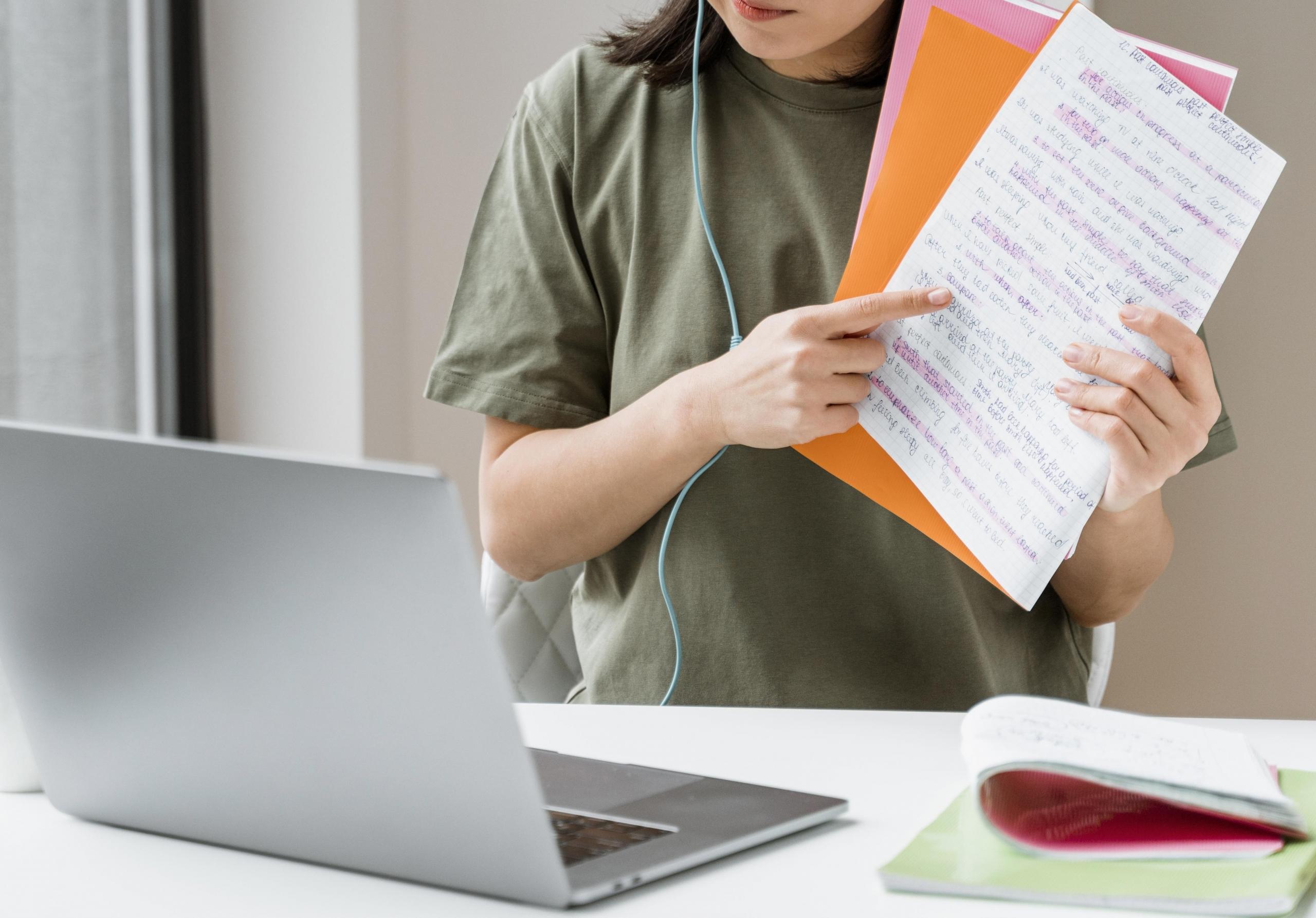mujer aprendiendo chino online con su laptop y sus apuntes en mano