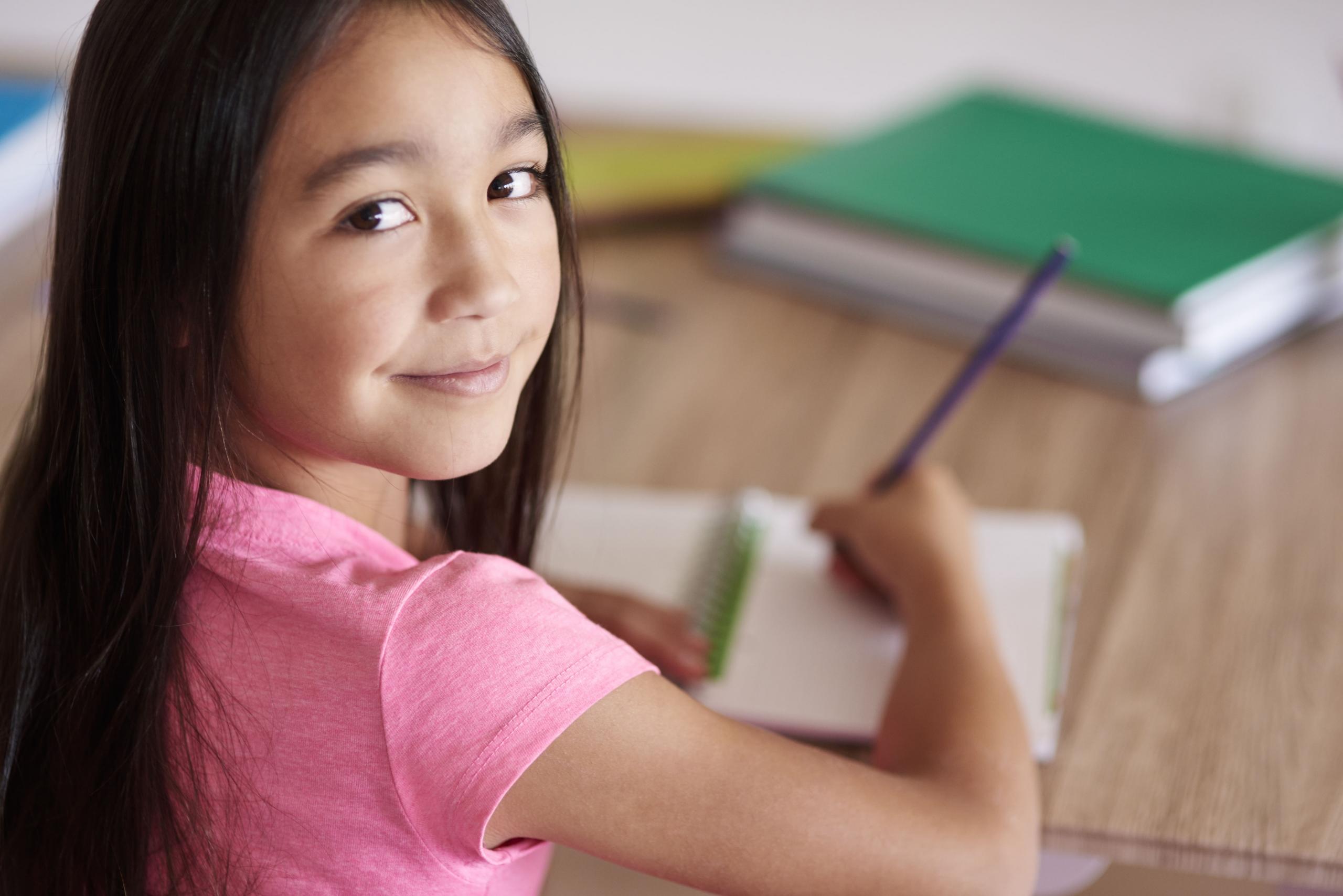 niña con lapiz y papel mirando a la camara