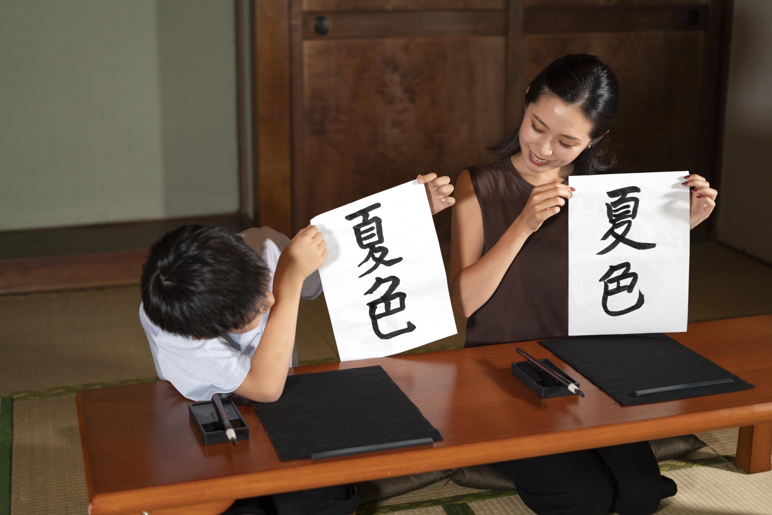 niño y una mujer sosteniendo frente a ellos unas hojas con la misma caligrafía china