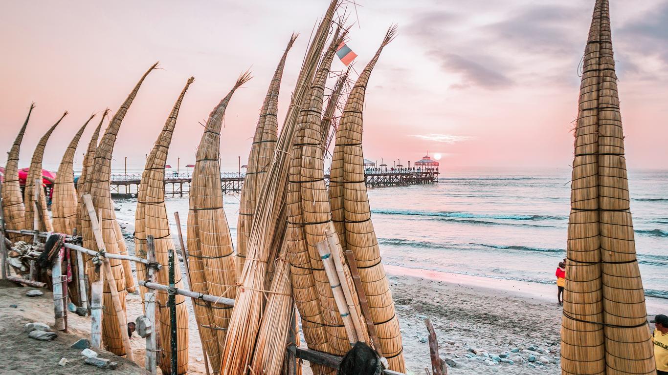 vista de la playa chiclaya con varios caballitos de totora alineados frente al mar