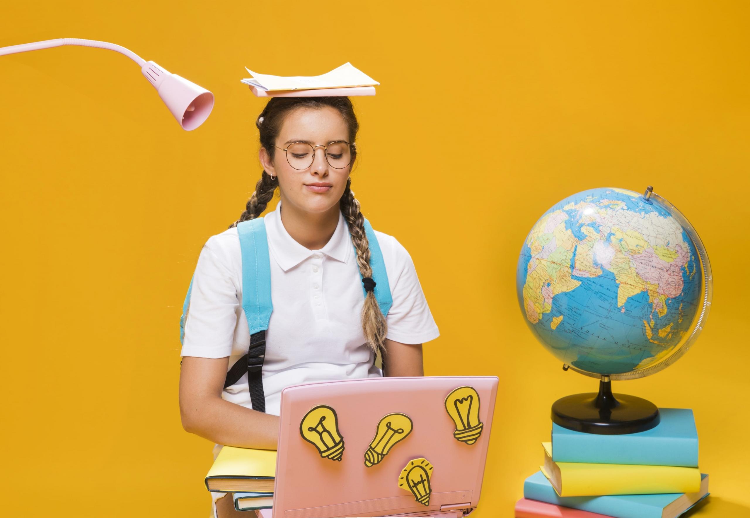 chica con una laptop, globo terráqueo y libros coloridos a su alrededor