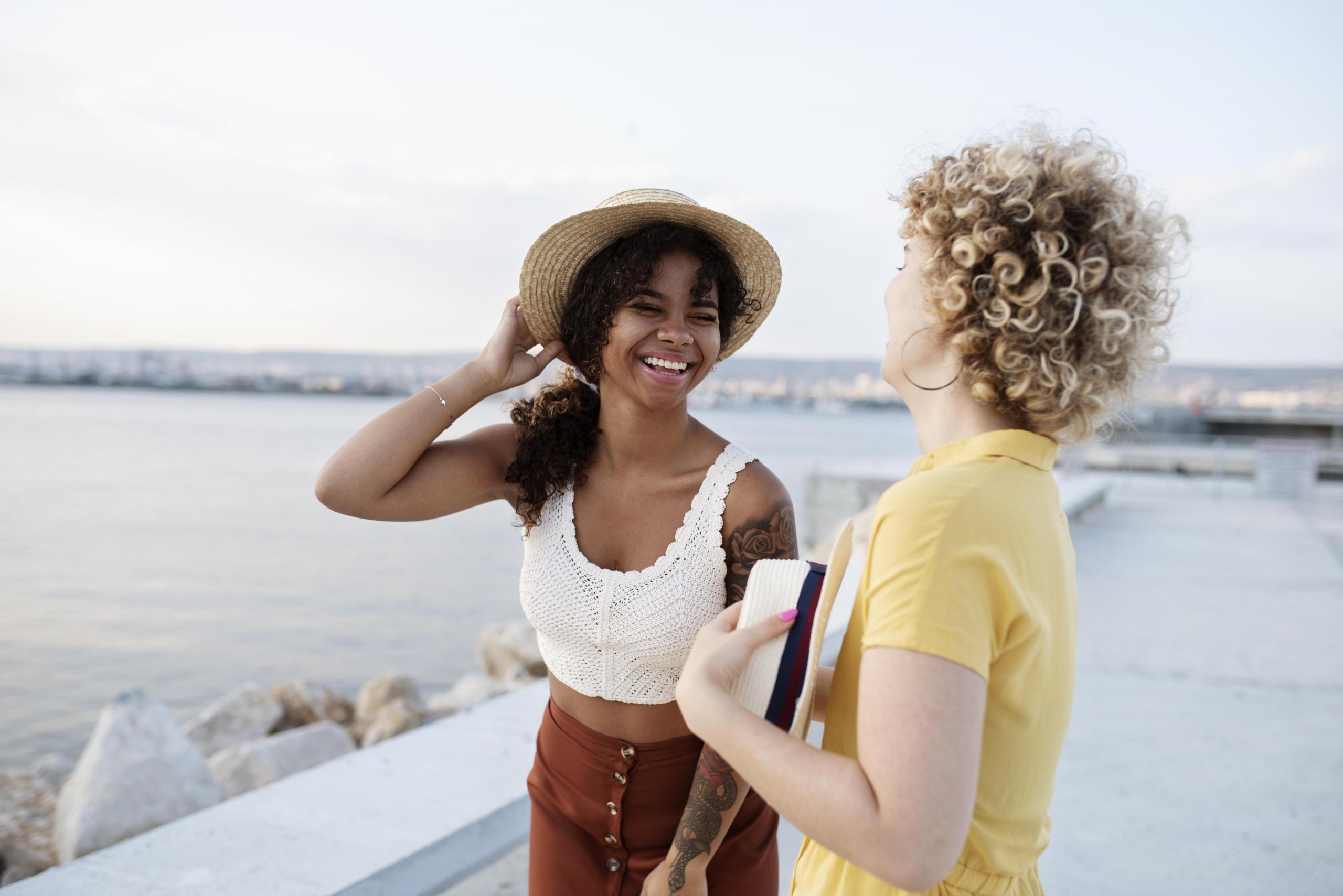 dos chicas conversando sonrientes frente a una playa