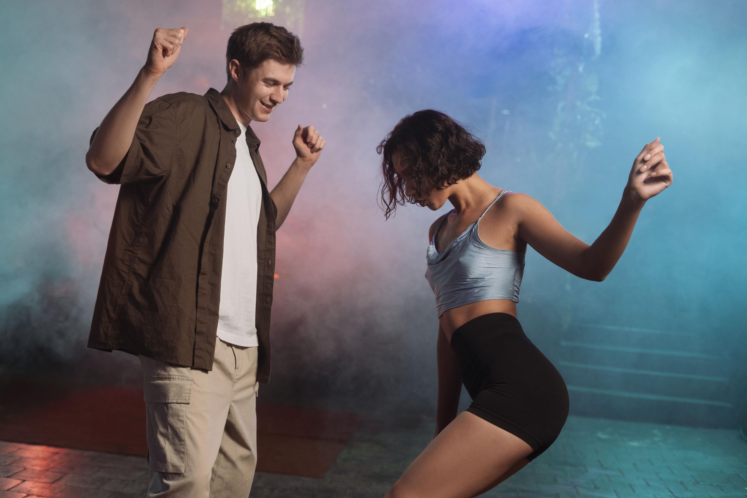 pareja de jóvenes bailando casualmente en un ambiente con luces y humo