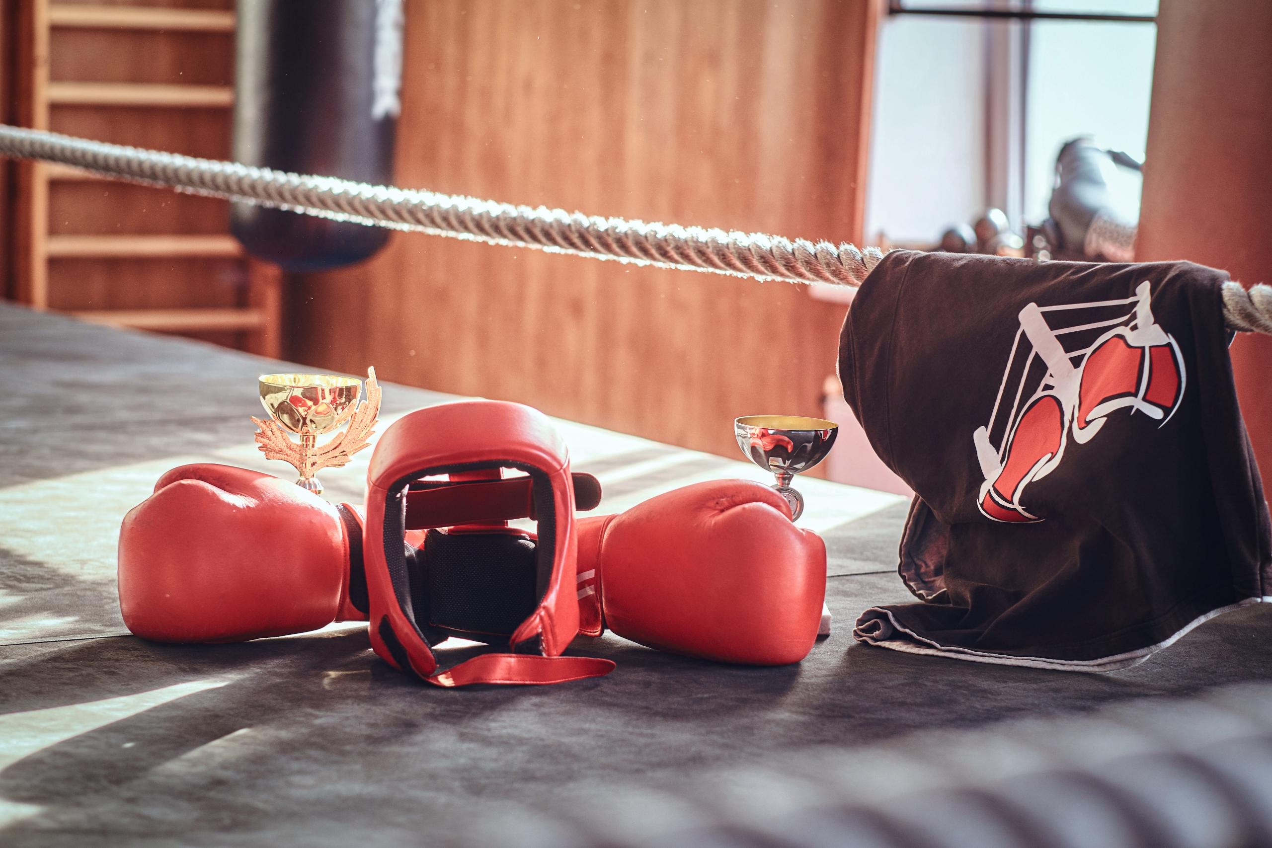 vista de guantes de boxeo, casco, polo y trofeos desde el ring