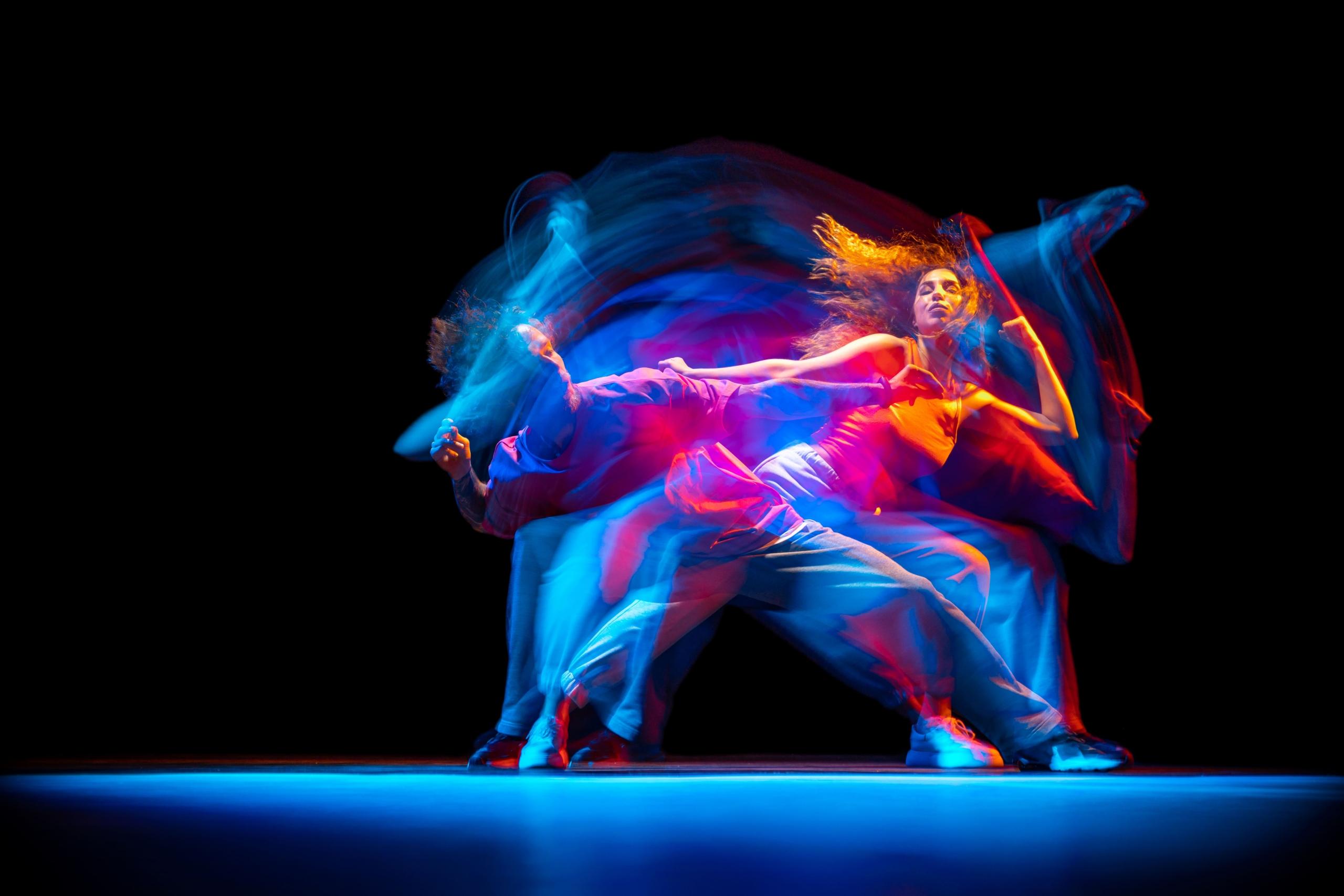 dos bailarinas con luces de colores y efecto borroso de sus movimientos previos