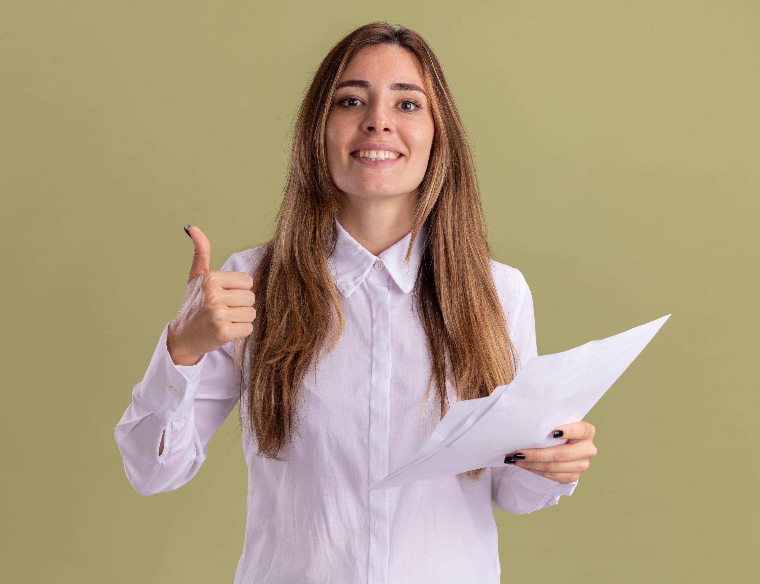 chica sonriente con pulgar hacia arriba sujetando unos examenes