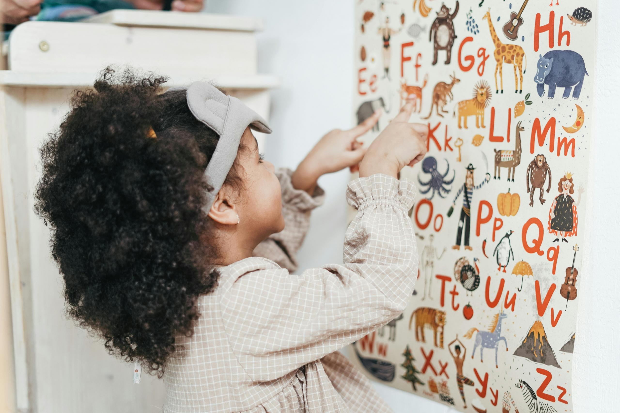 niña jugando con un tablero de figuras y letras en la pared
