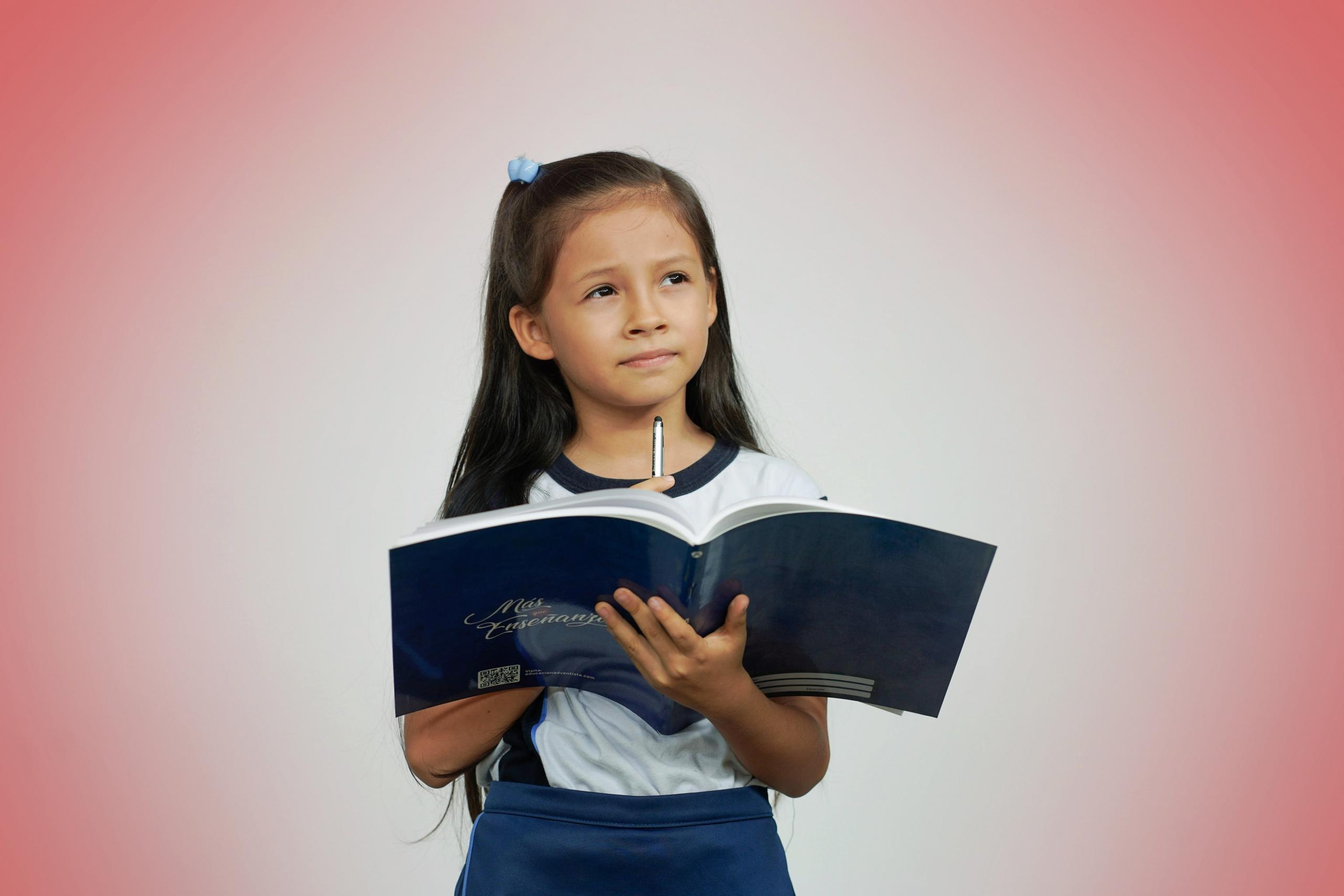 niña pensativa sosteniendo un libro en su mano