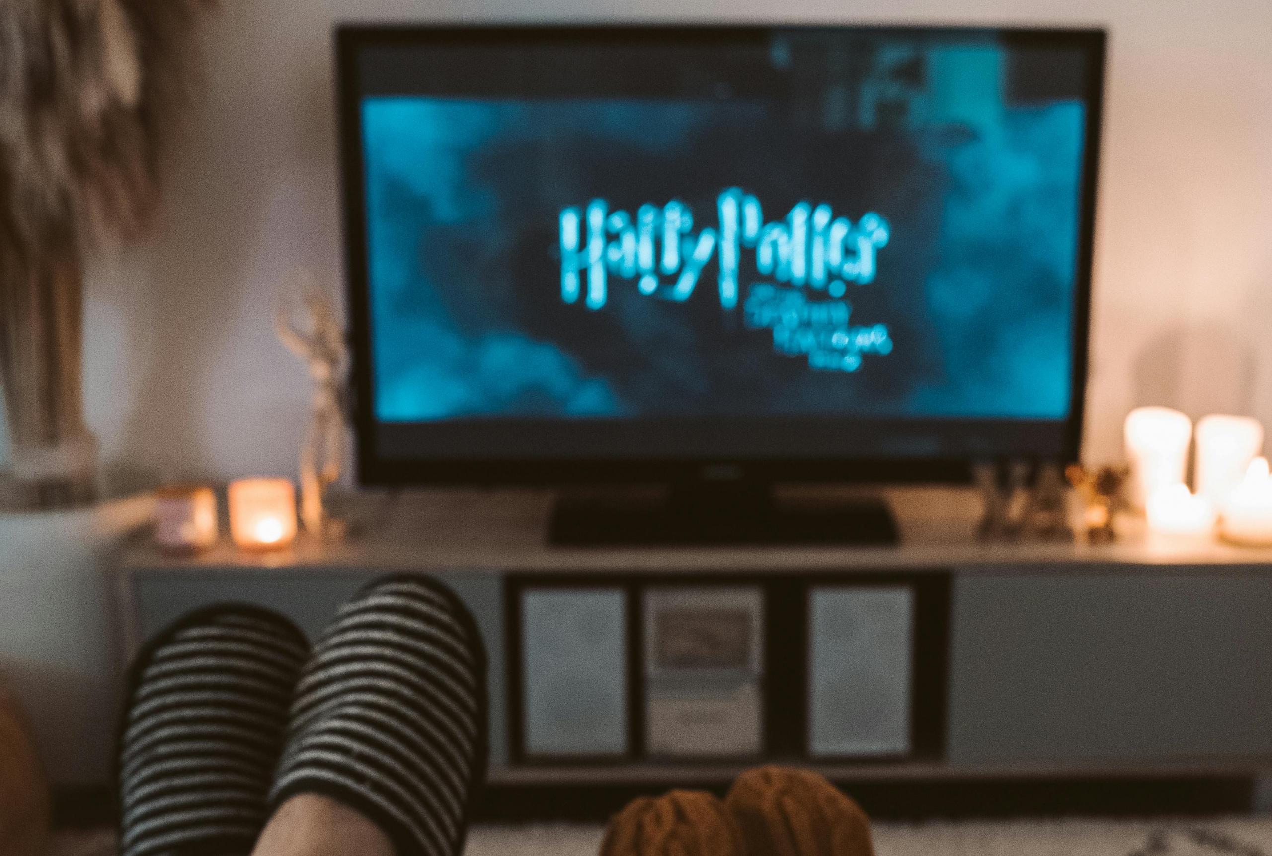 tv con logo de Harry Potter y pies con pantuflas frente al televisor